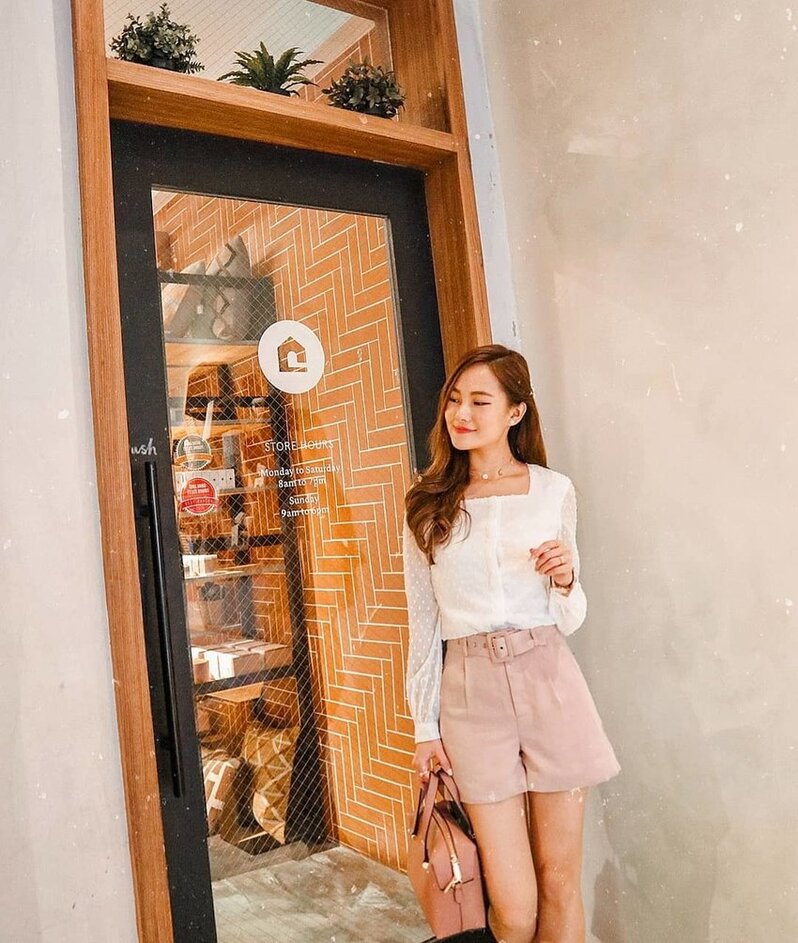 Lady outside a cafe A lady wearing a white blouse and pink shorts is standing outside the entrance of a cafe.