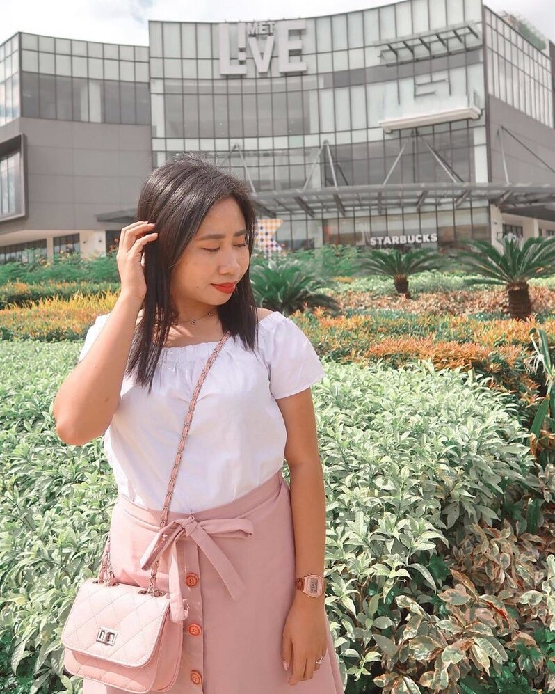 Girl in a pink skirt Girl wearing a pink a-line button-up miniskirt is standing in a field of plants.