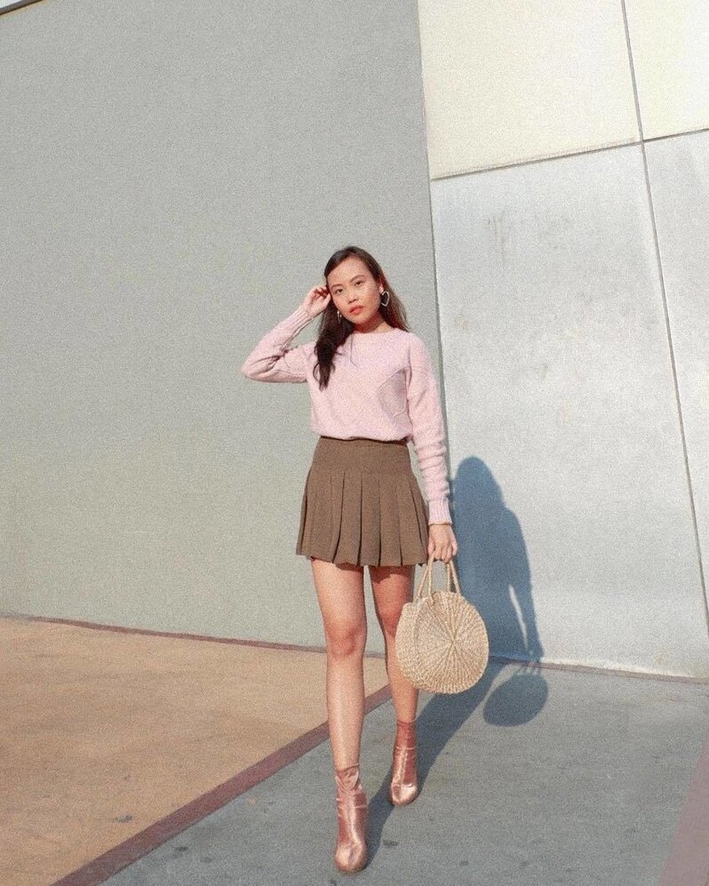 Girl in preppy attire A girl wearing a pink sweater tucked in a brown pleated miniskirt