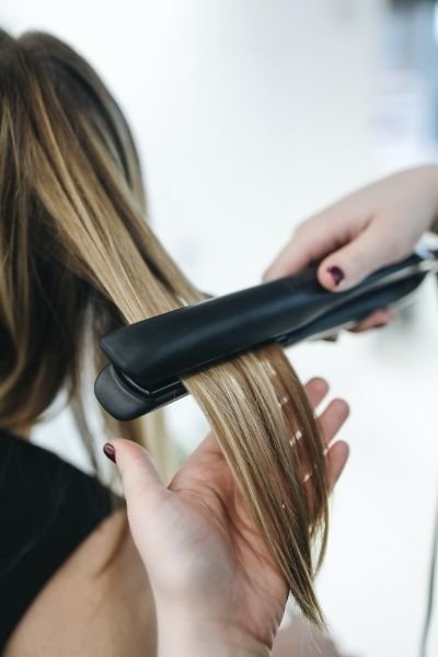 Woman's hair being straightened with a flat iron
