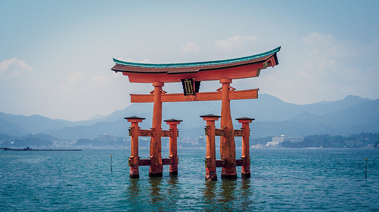 A red torii gate standing in the middle of the sea