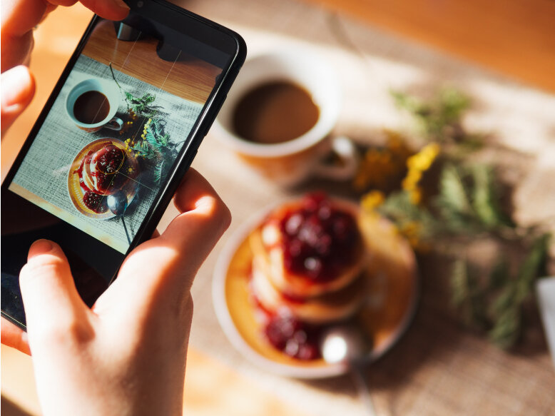 A mobile phone user captures a photo of Japanese pancakes with raspberry syrup