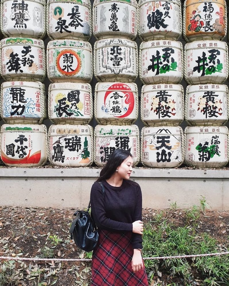 Woman in front of sake barrels at Meiji Shrine