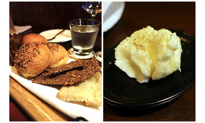 A plate full of different varieties of bread and a plate with a scoop of seasoned butter.