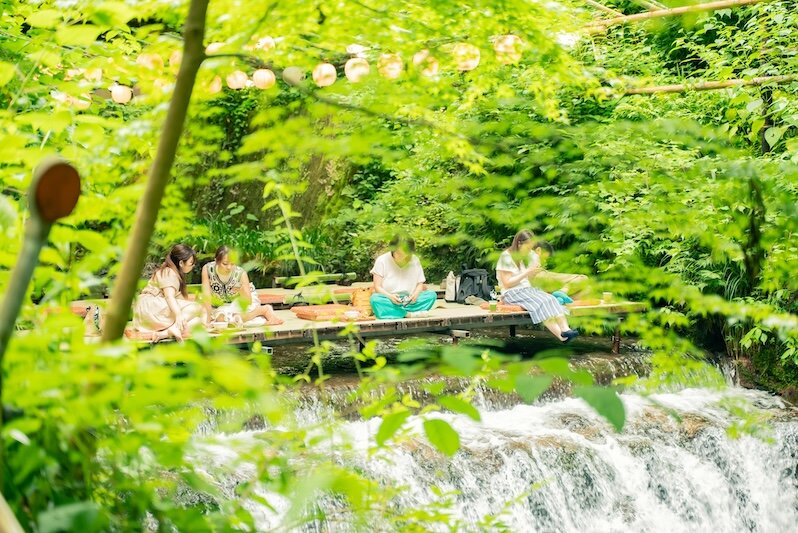 People relaxing on a tatami bed beside the river. 