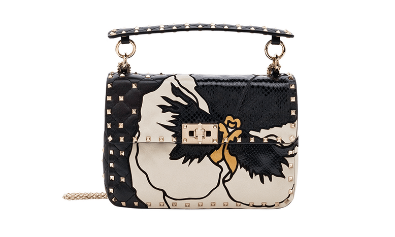 A black, studded bag with a white elegant flower art print.